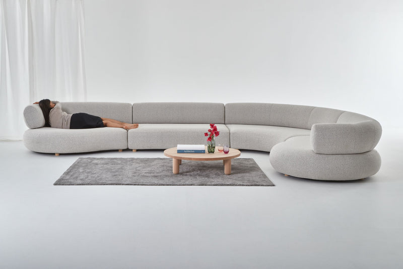 Eclipse curved designer modular sofa shown with woman lying in grey