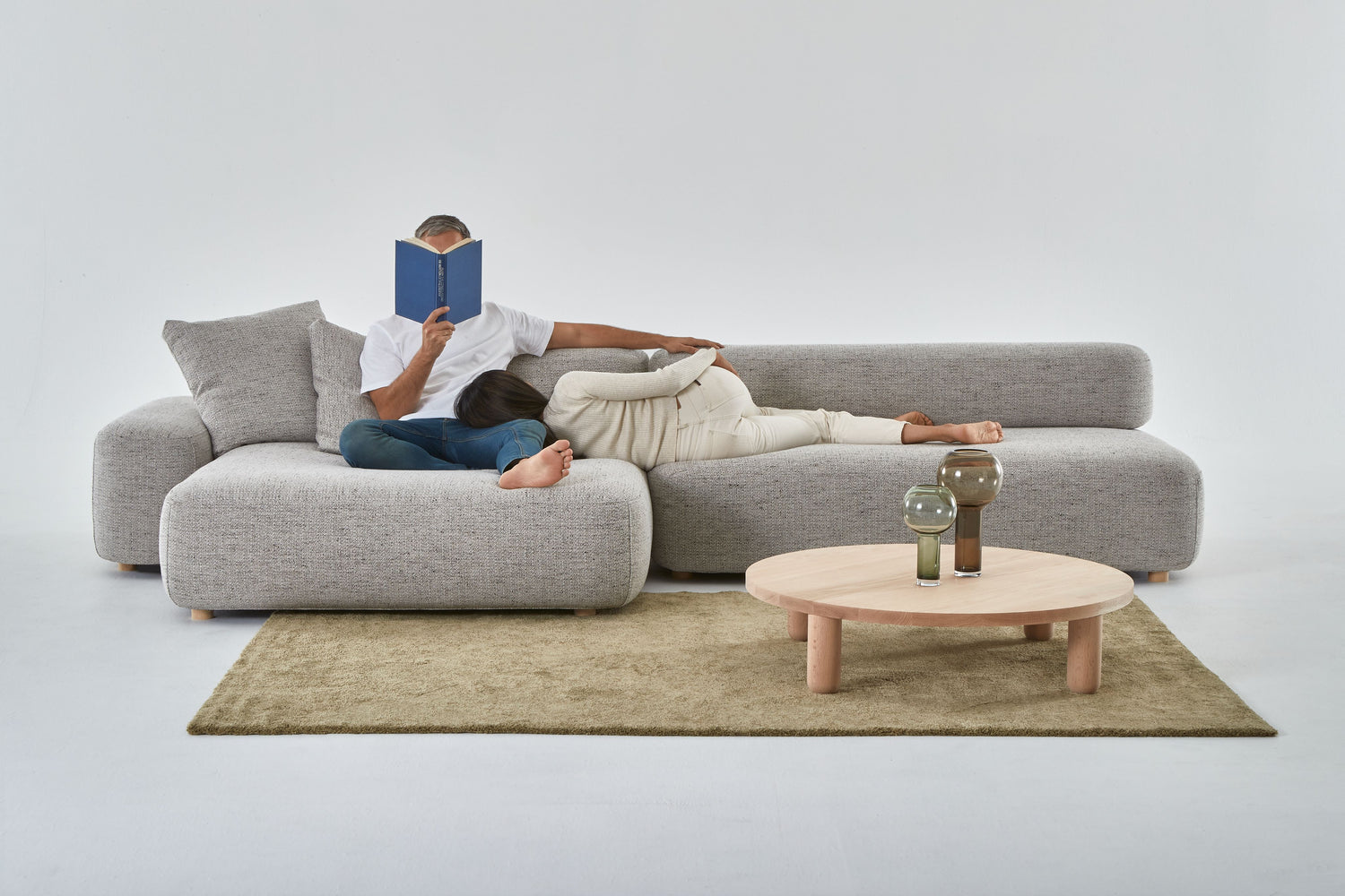 Man and woman relaxing on the Flux chaise and rectangle. Man is reading, woman is asleep on his lap.