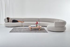 Eclipse curved designer modular sofa shown with woman lying in grey