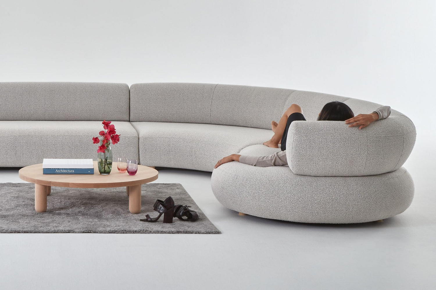 The curved end of the Eclipse designer modular sofa, shown with a woman lying on the curved end.
