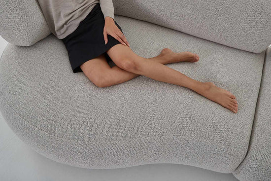 A left curved end of the Eclipse modular sofa with a woman lying on it wearing a black skirt.