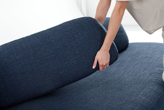 Woman moving moveable back-rest of Ethos Max blue sofa.