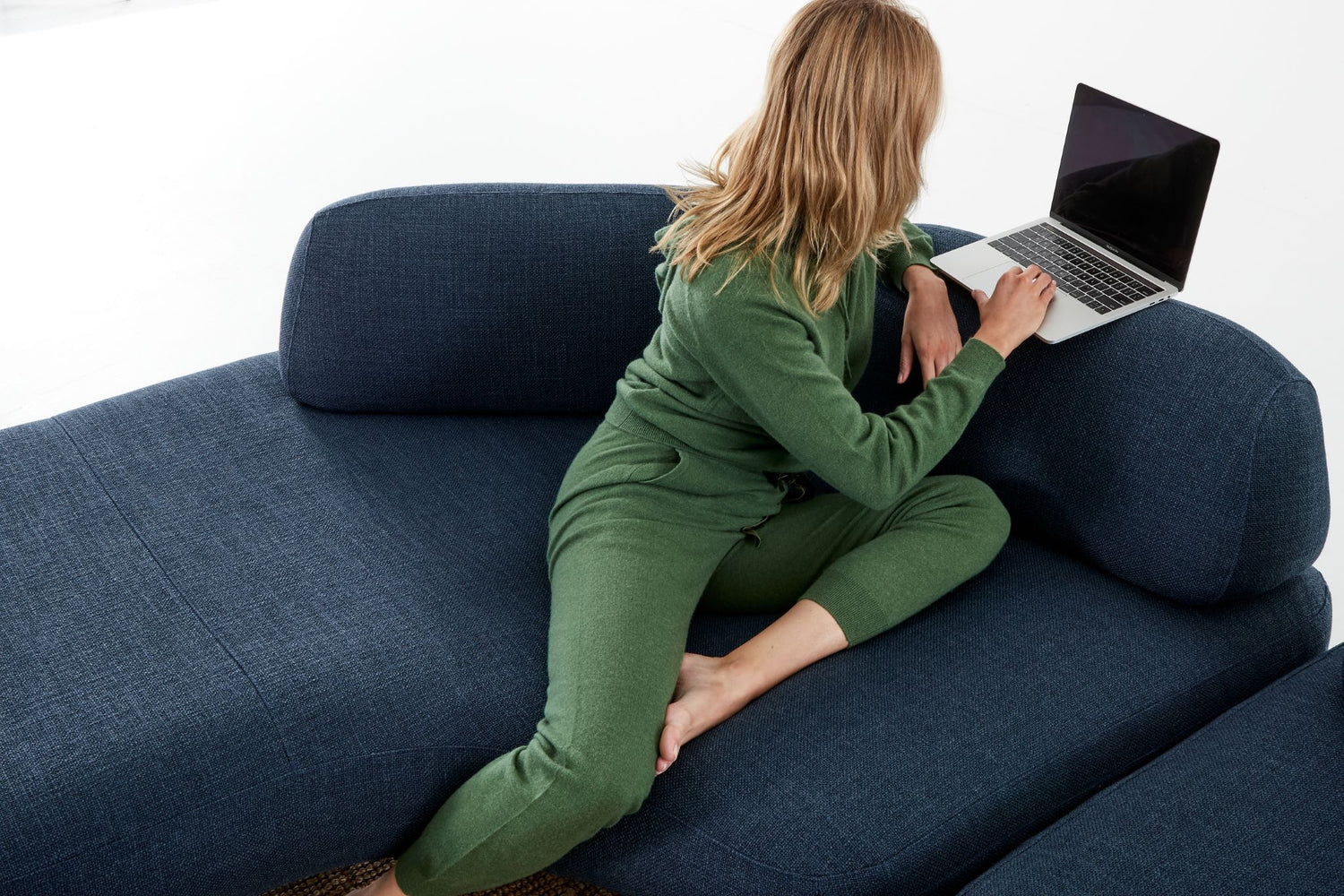 Woman in corner of Ethos Max plus sofa curved module using laptop which is on the back-rest.
