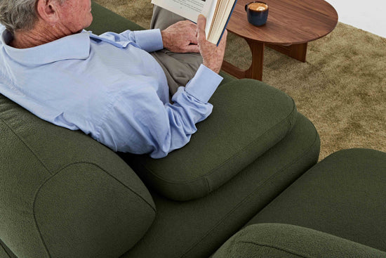 Man comfortably sitting reading on Ethos Plus green sofa by E9 Design with table and coffee