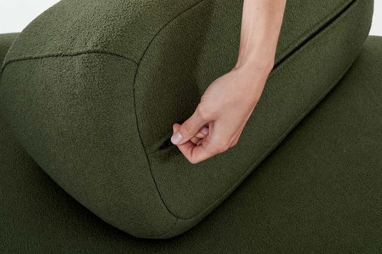 A hand unzipping the removable cover of a Green Ethos Plus sofa moveable back.