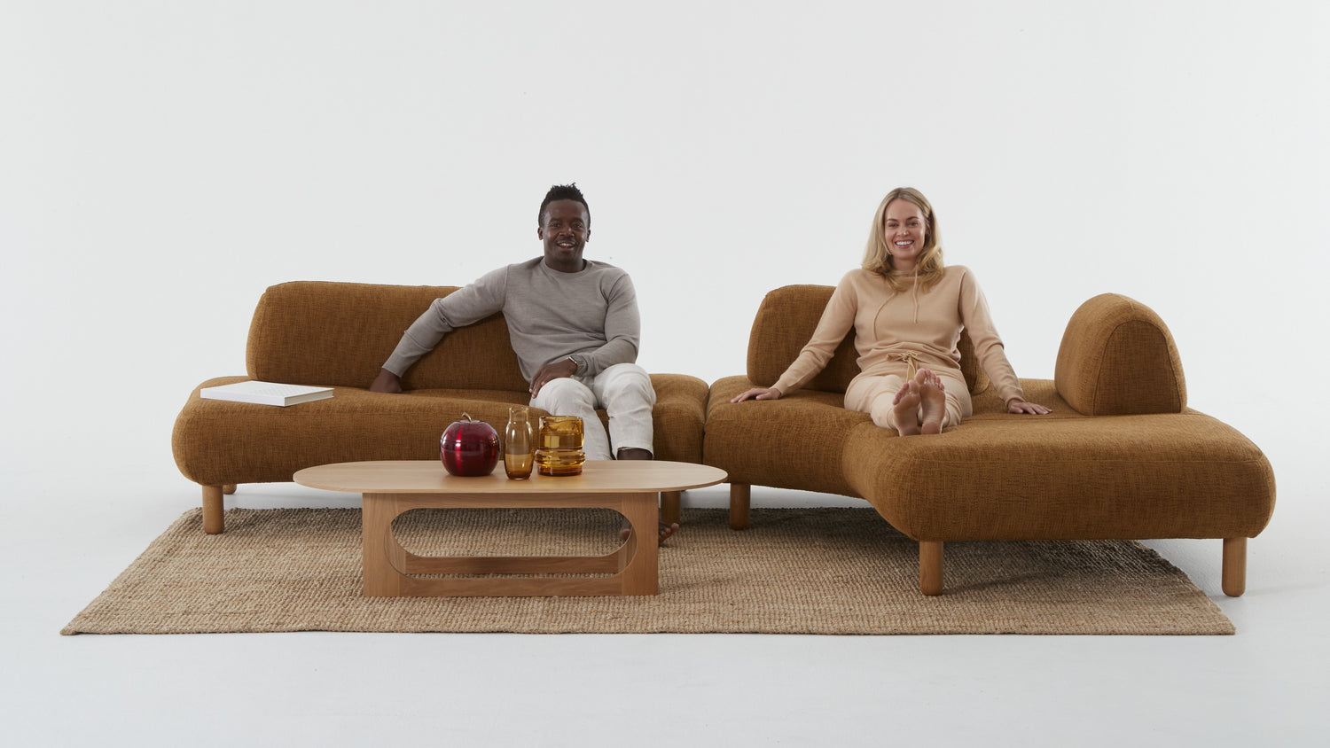 Two modules of the Locus modular lounge with an Ethos table and a man sitting on one and a woman lying on the other.